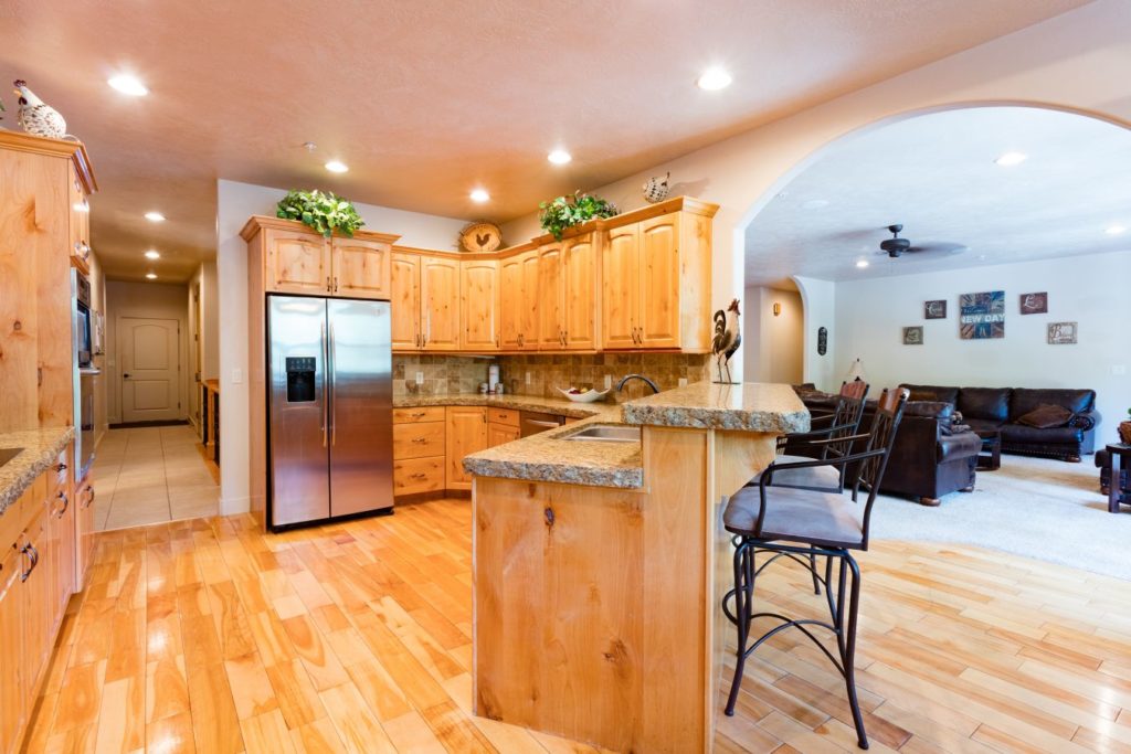 Open kitchen with wood cabinets leading into a cozy living room