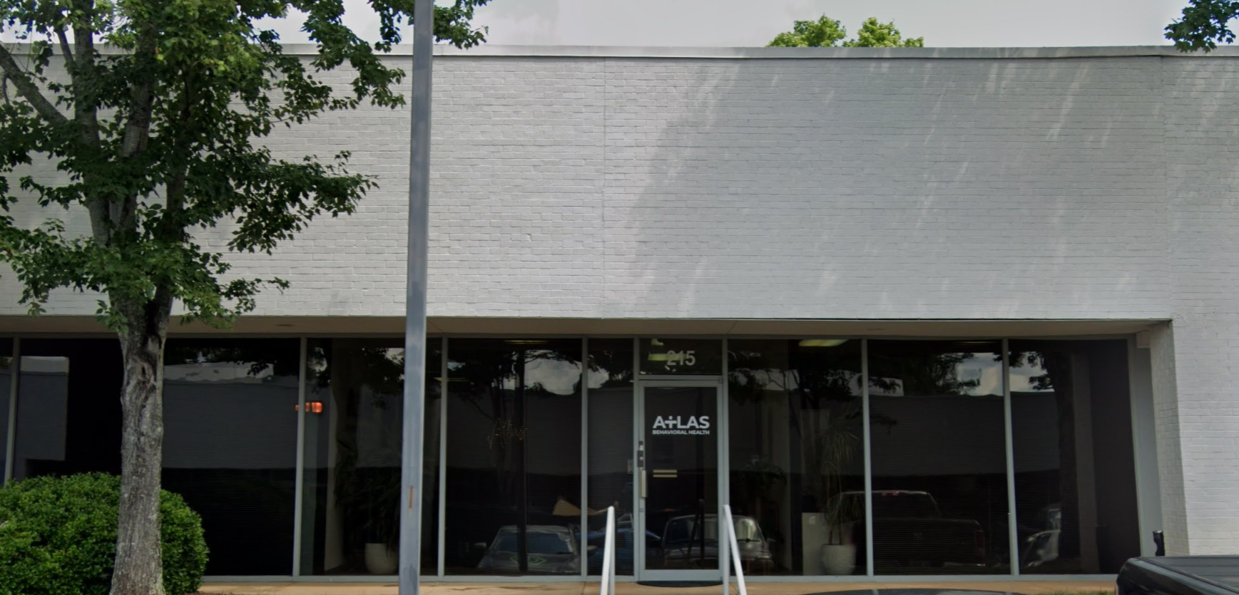 Exterior of a white rehab facility with large glass windows and signage.