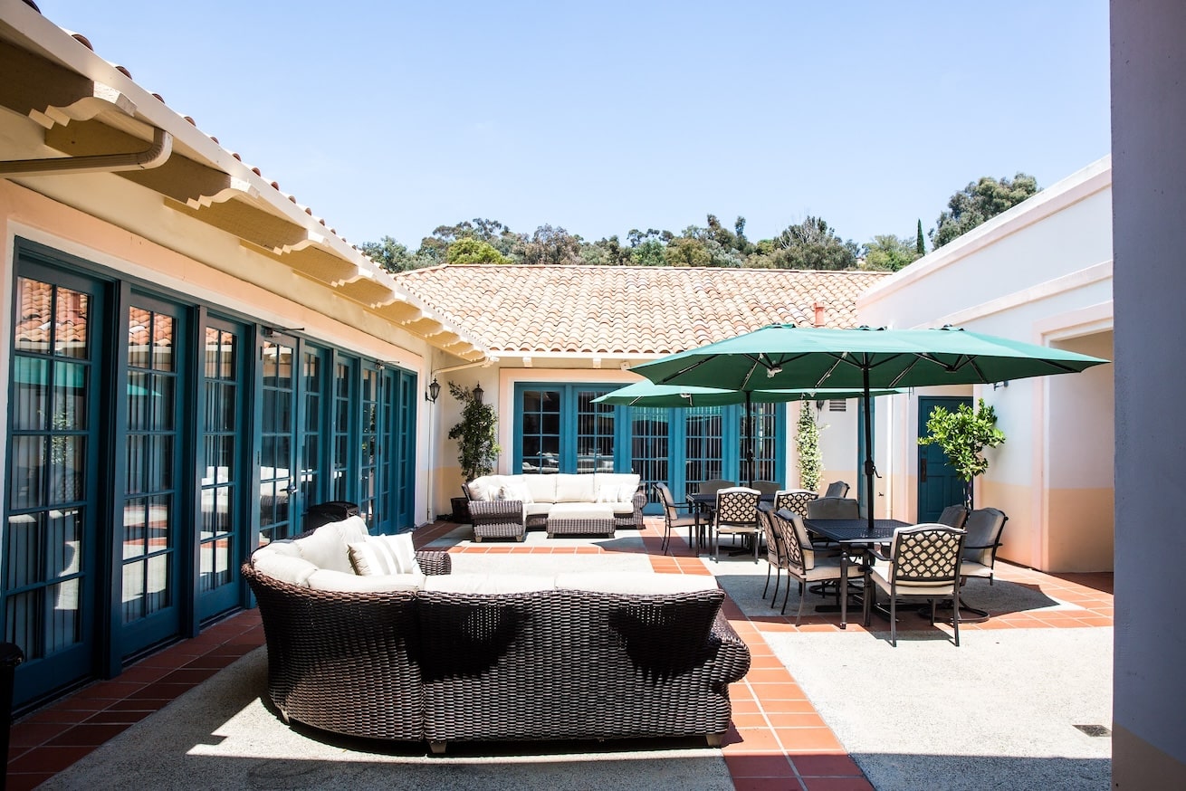 An outdoor courtyard with seating and a green umbrella.