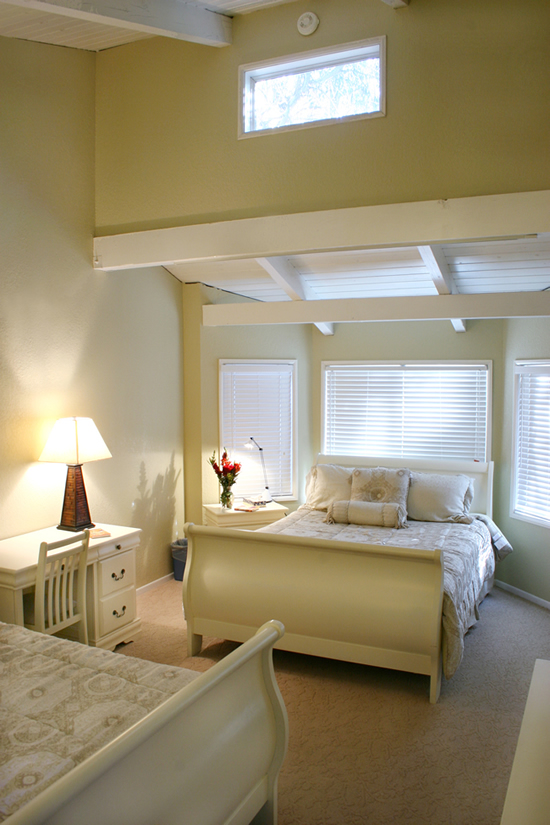 Bright bedroom with two white beds and soft natural lighting
