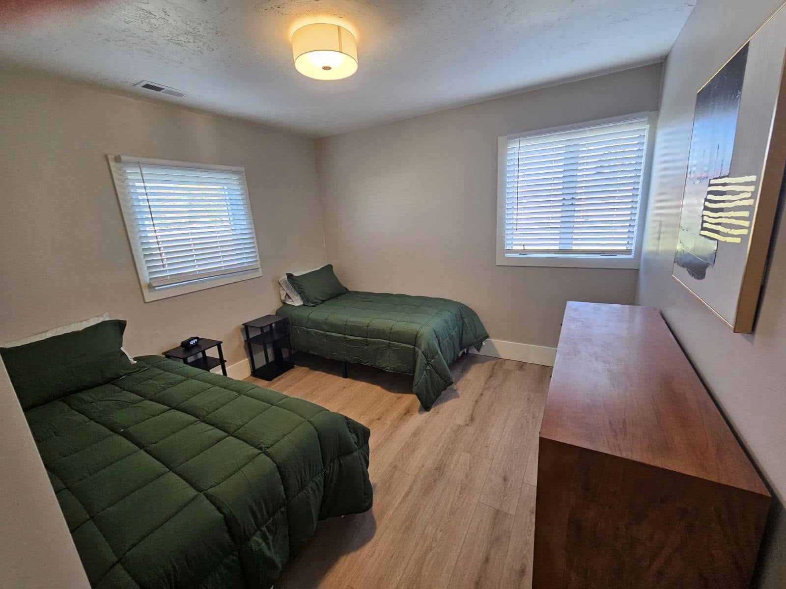 Two twin beds with green bedding and wood flooring