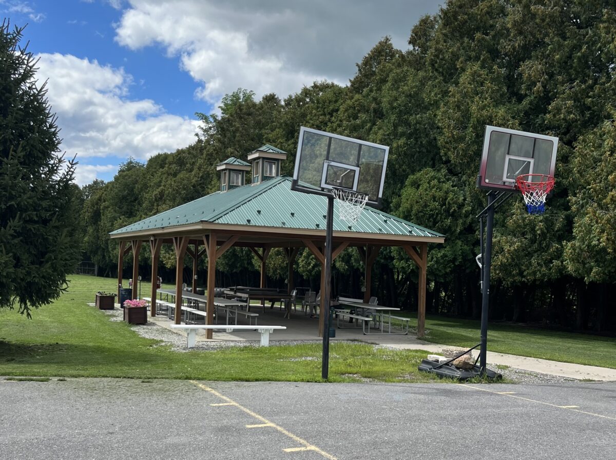 Pavilion and basketball hoops near wooded rehab grounds