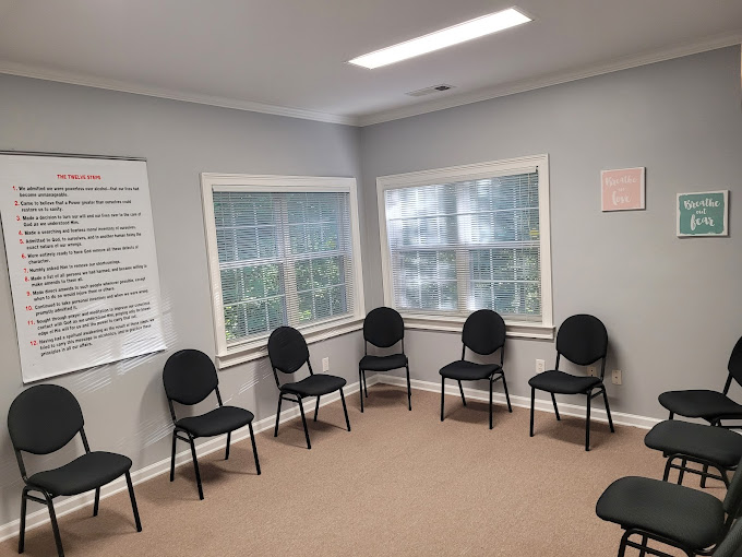 A group therapy room with black chairs arranged in a circle.