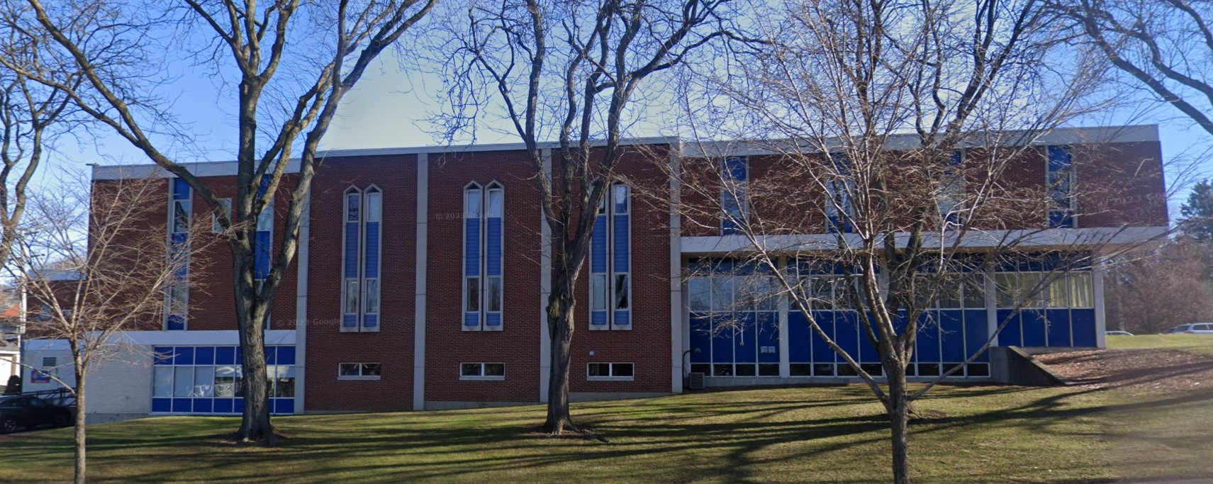 A large brick building with tall windows, surrounded by leafless trees.