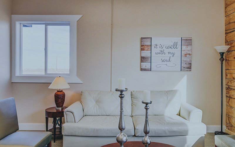 Cozy lounge with a white couch, lamps, and framed wall art.
