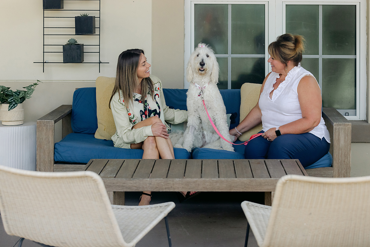 Two women with therapy dog on outdoor couch