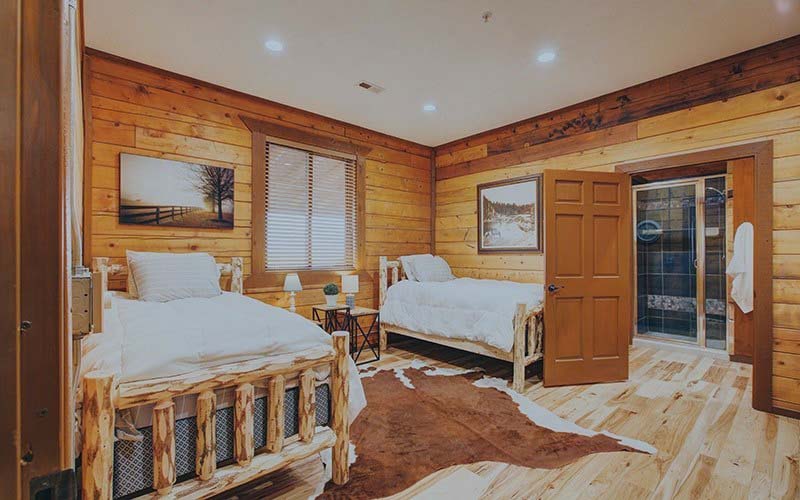 Rustic bedroom with wooden walls, two twin beds, and western decor.
