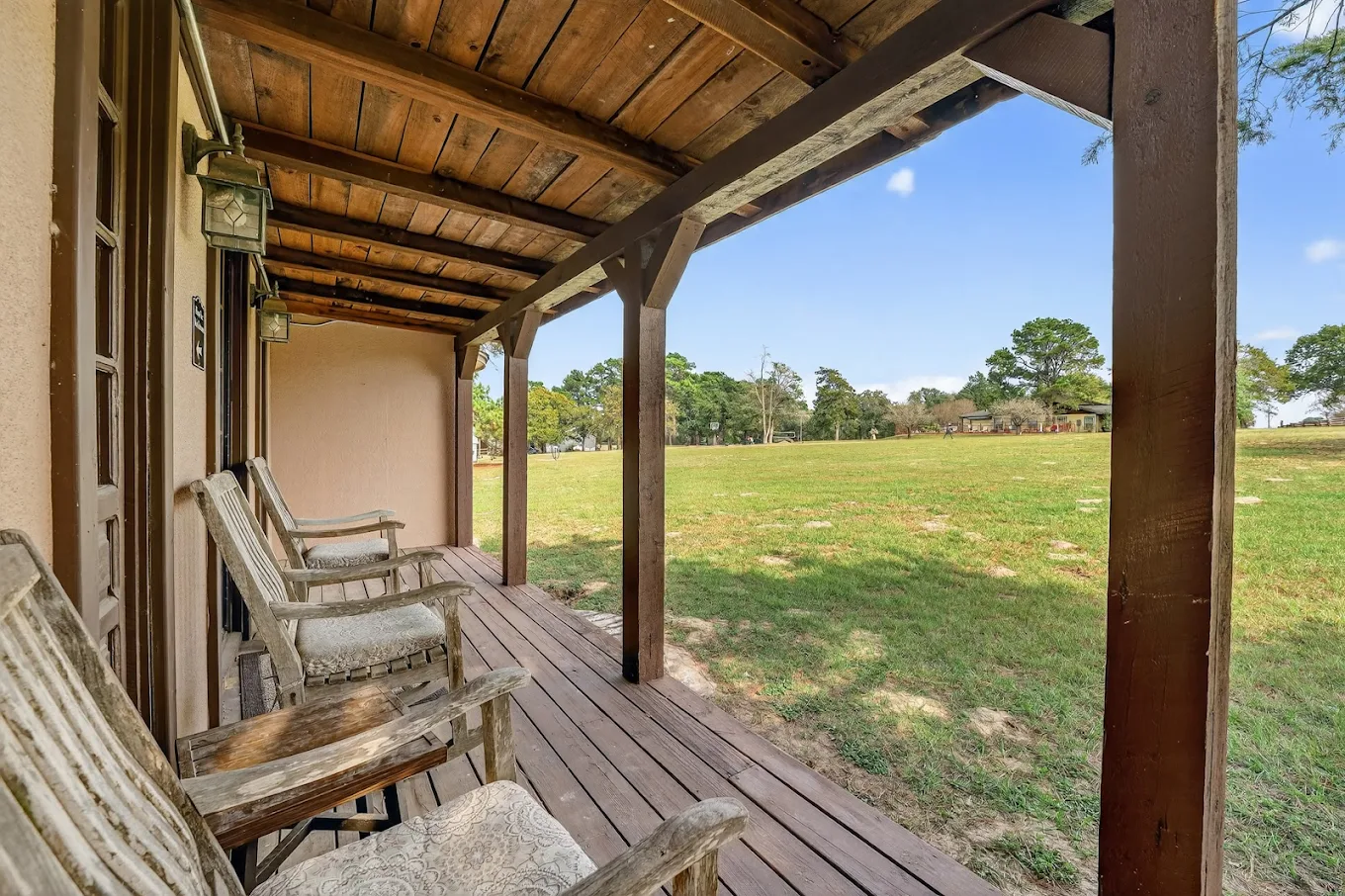 Covered outdoor patio with seating overlooking open grassy grounds