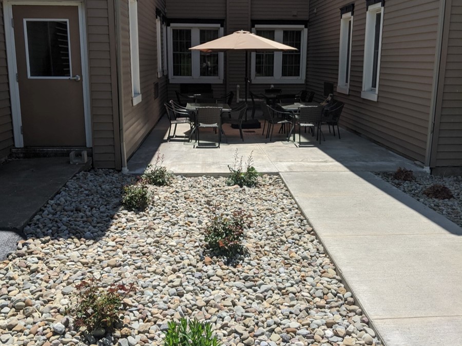 Courtyard with tables and umbrella seating between facility wings.