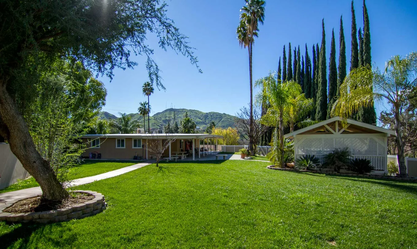 Spacious grassy courtyard with trees and mountain views.