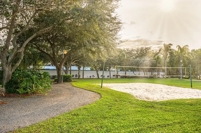 Sand volleyball court with net and trees nearby