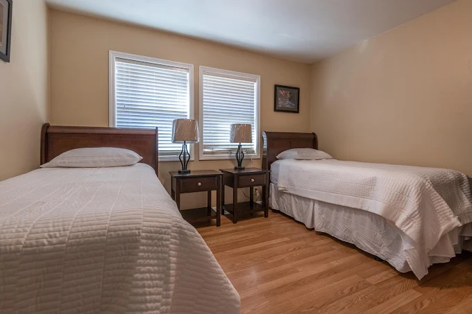 Two twin beds with white linens in shared bedroom