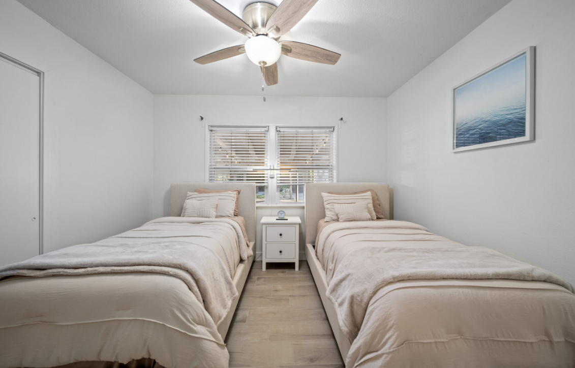 Two twin beds with soft beige linens in a shared bedroom