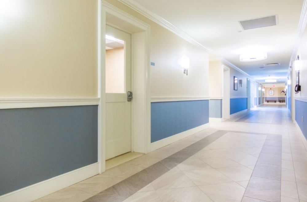 Long hallway with artwork, doors, and directional signs.