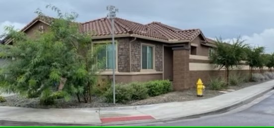 One-story brick house on a corner lot with desert landscaping
