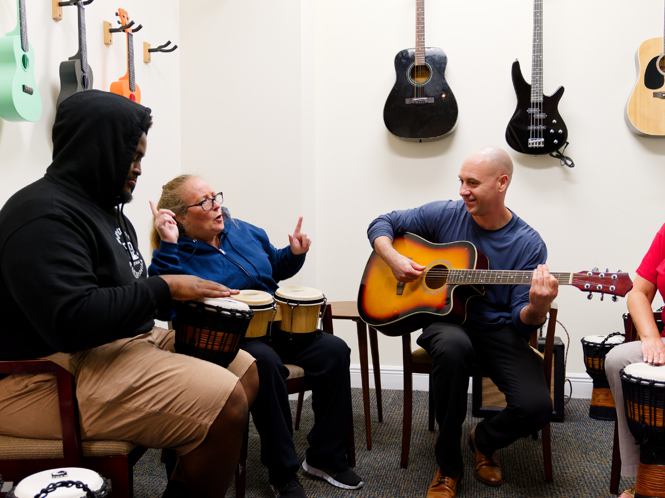 Clients playing drums and guitar in music therapy group