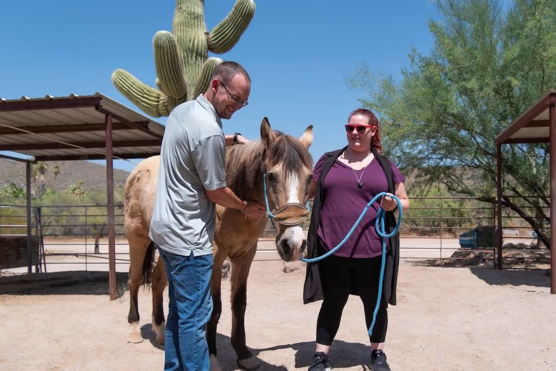 Two people guiding a horse at equine therapy area