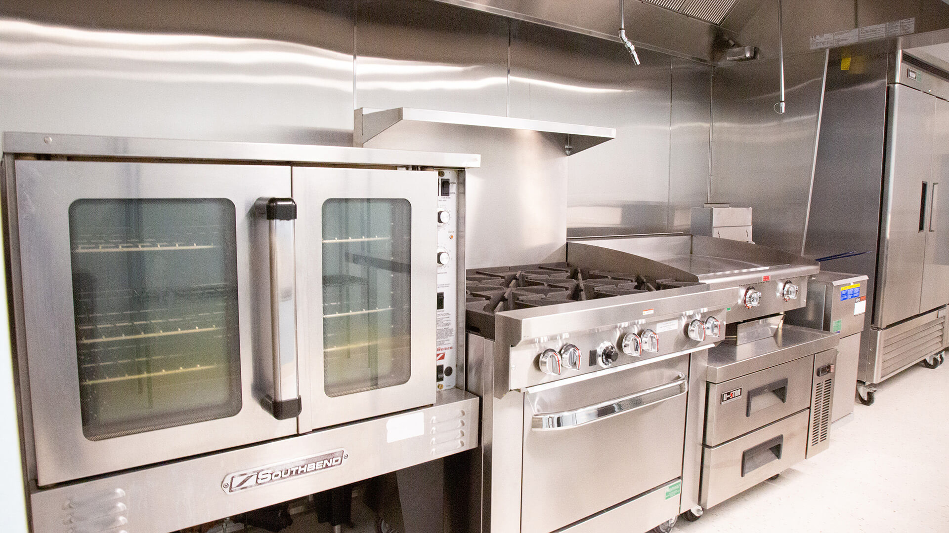 Kitchen with a large oven, stove, and refrigerators.