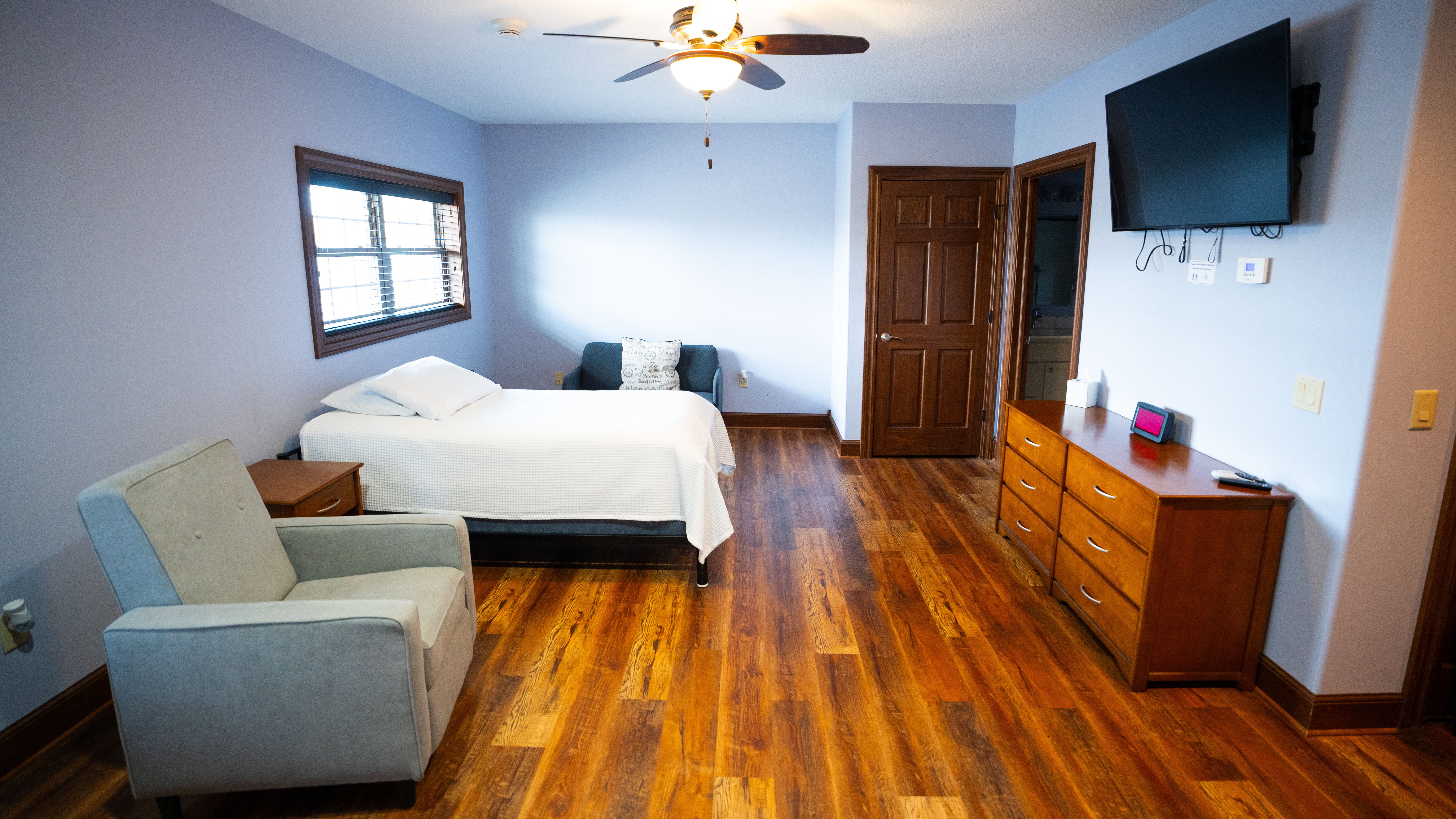 Spacious bedroom with TV, dresser, and armchair