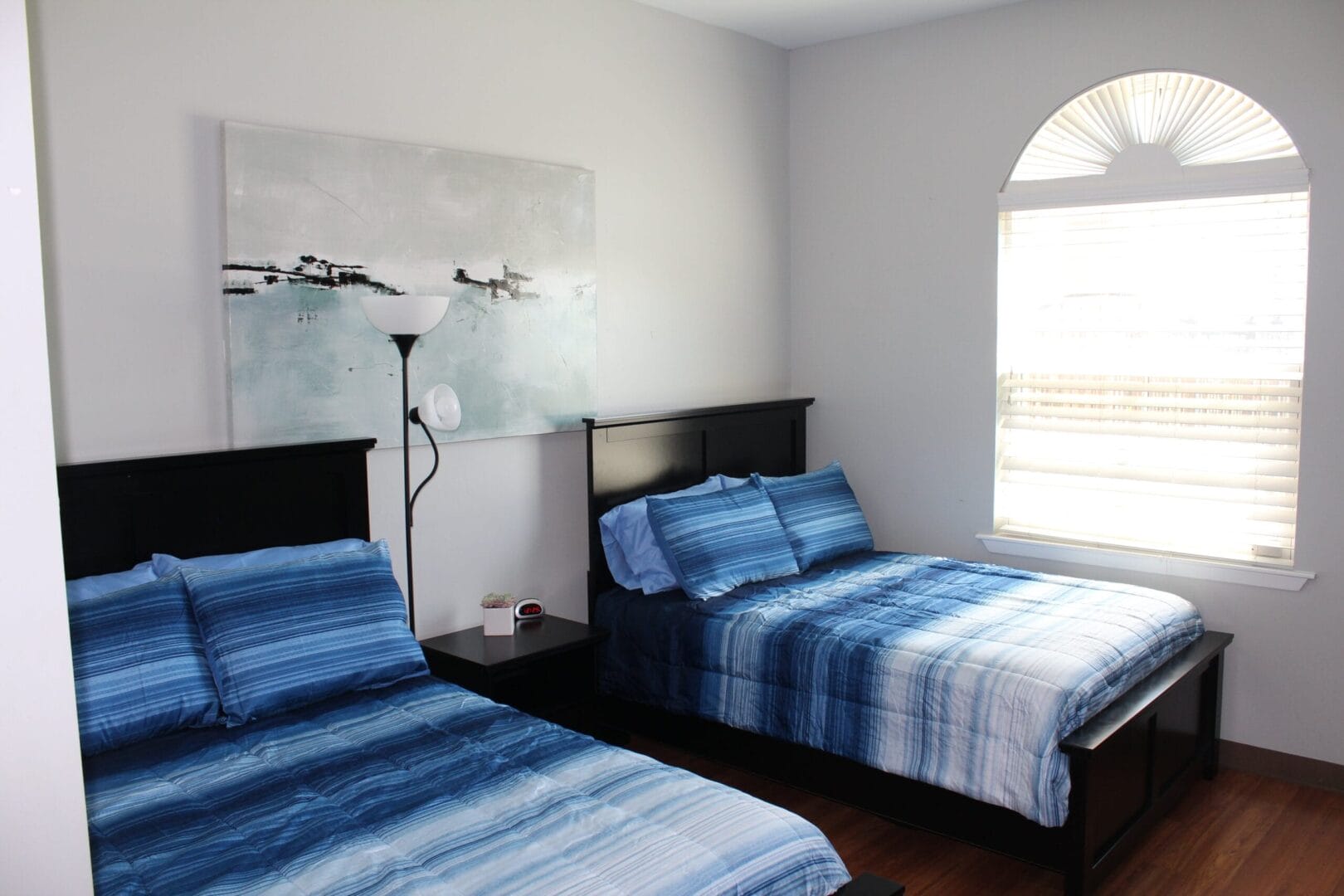 Bedroom with two  beds, a large window and wall art.