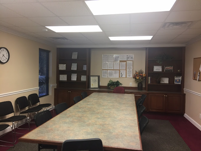 A meeting room with a large table, chairs, and bulletin boards on the wall.