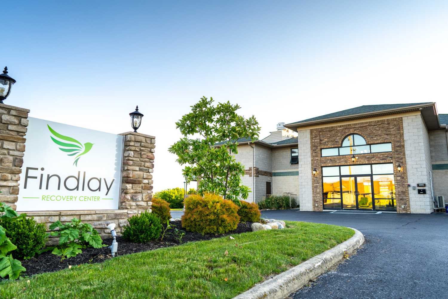 The exterior of Findlay Recovery Center with a sign and landscaping.