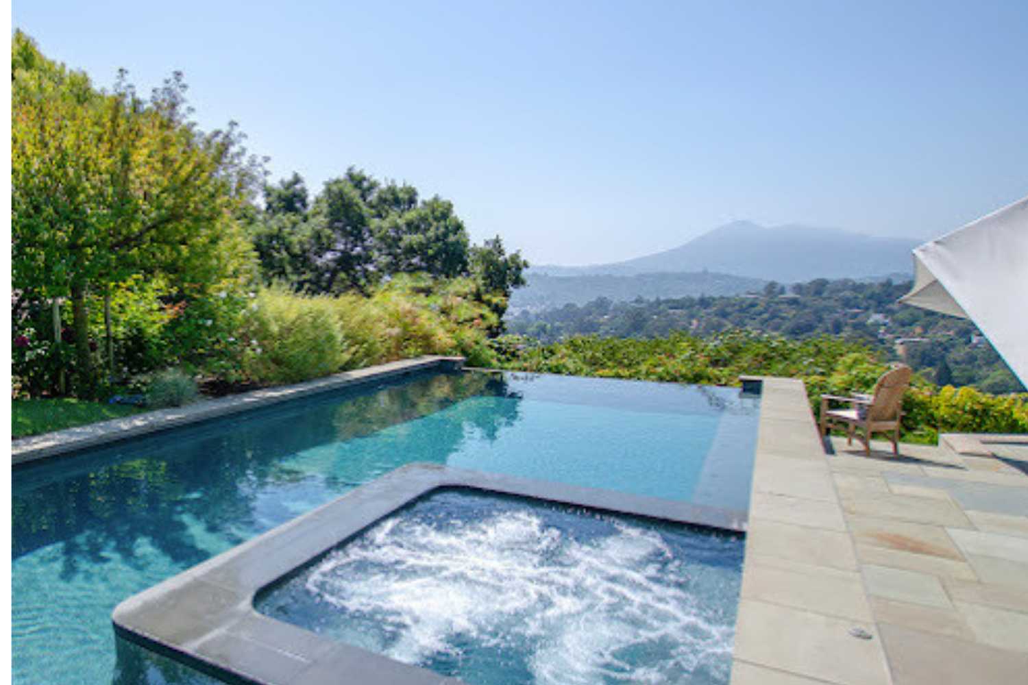 Outdoor pool with spa overlooking scenic hills.