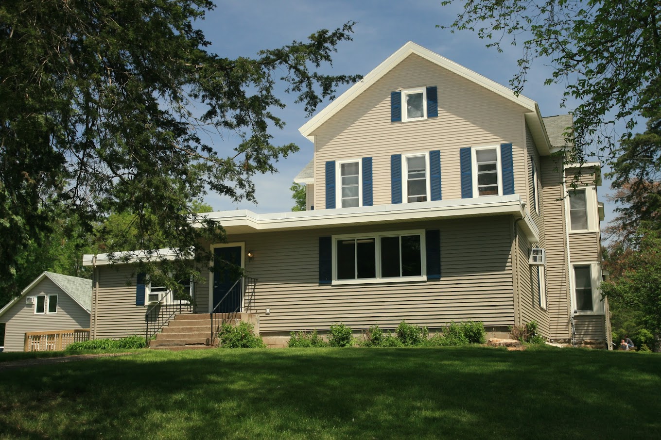 Tan house-style facility with blue shutters on a grassy hill