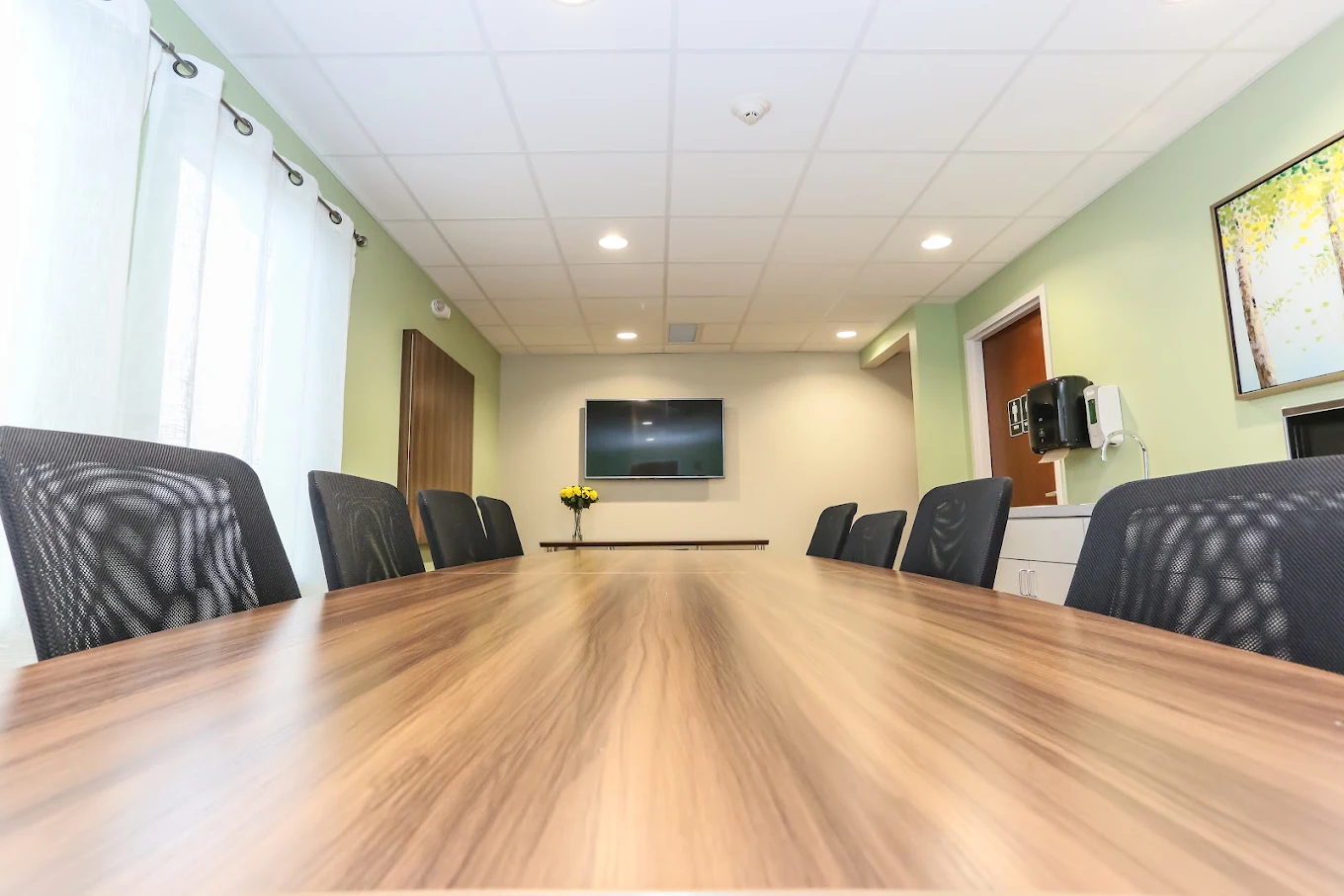 Long meeting table surrounded by black office chairs