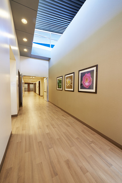 Rehab hallway with wood floors and framed floral art