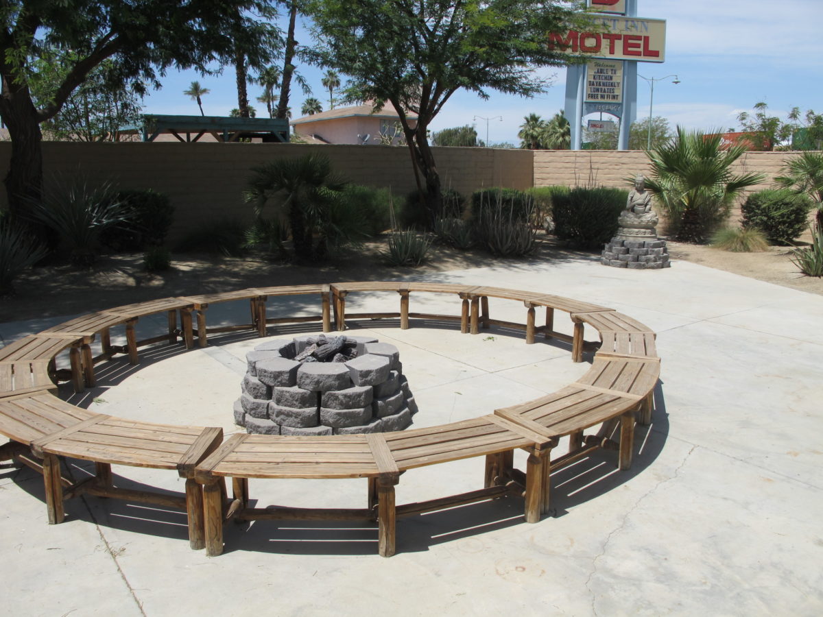 Outdoor fire pit with wooden circular bench seating.