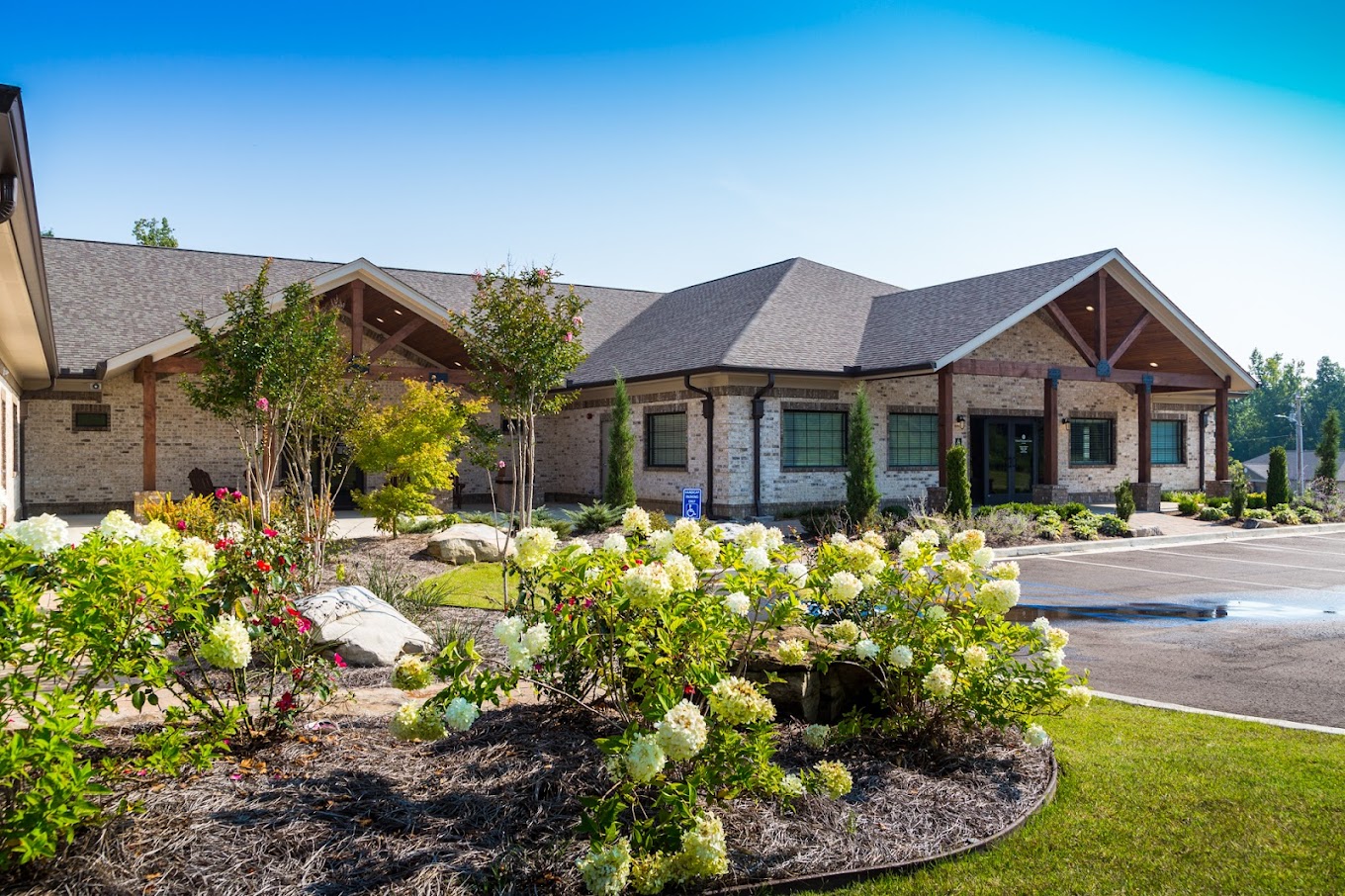Exterior of a brick rehab facility with landscaped flowers and greenery.