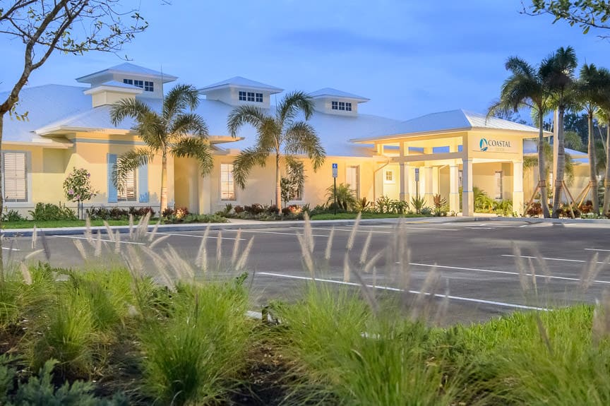 Exterior of facility with palm trees and parking lot