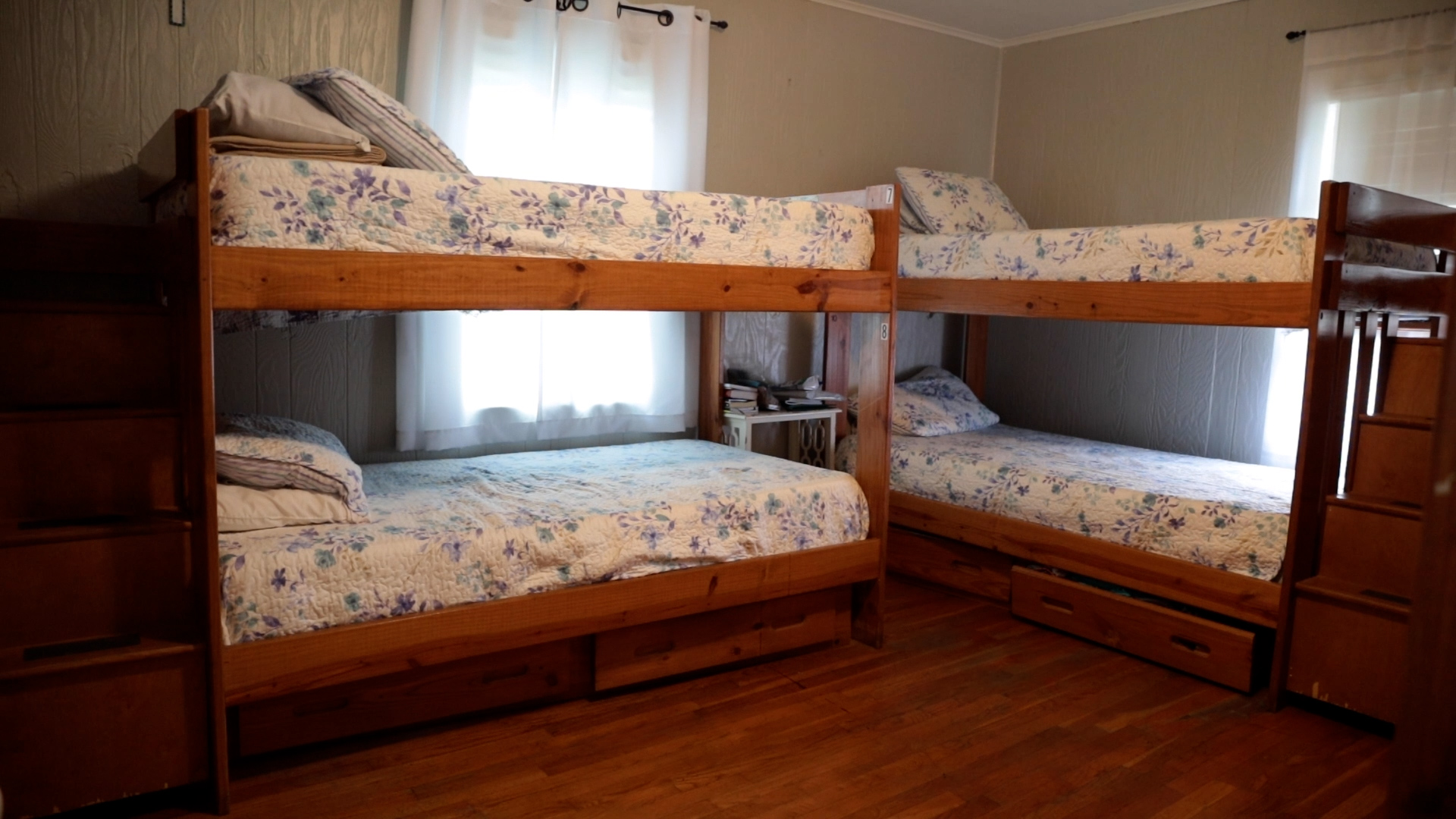 Room with two wooden bunk beds and floral quilts