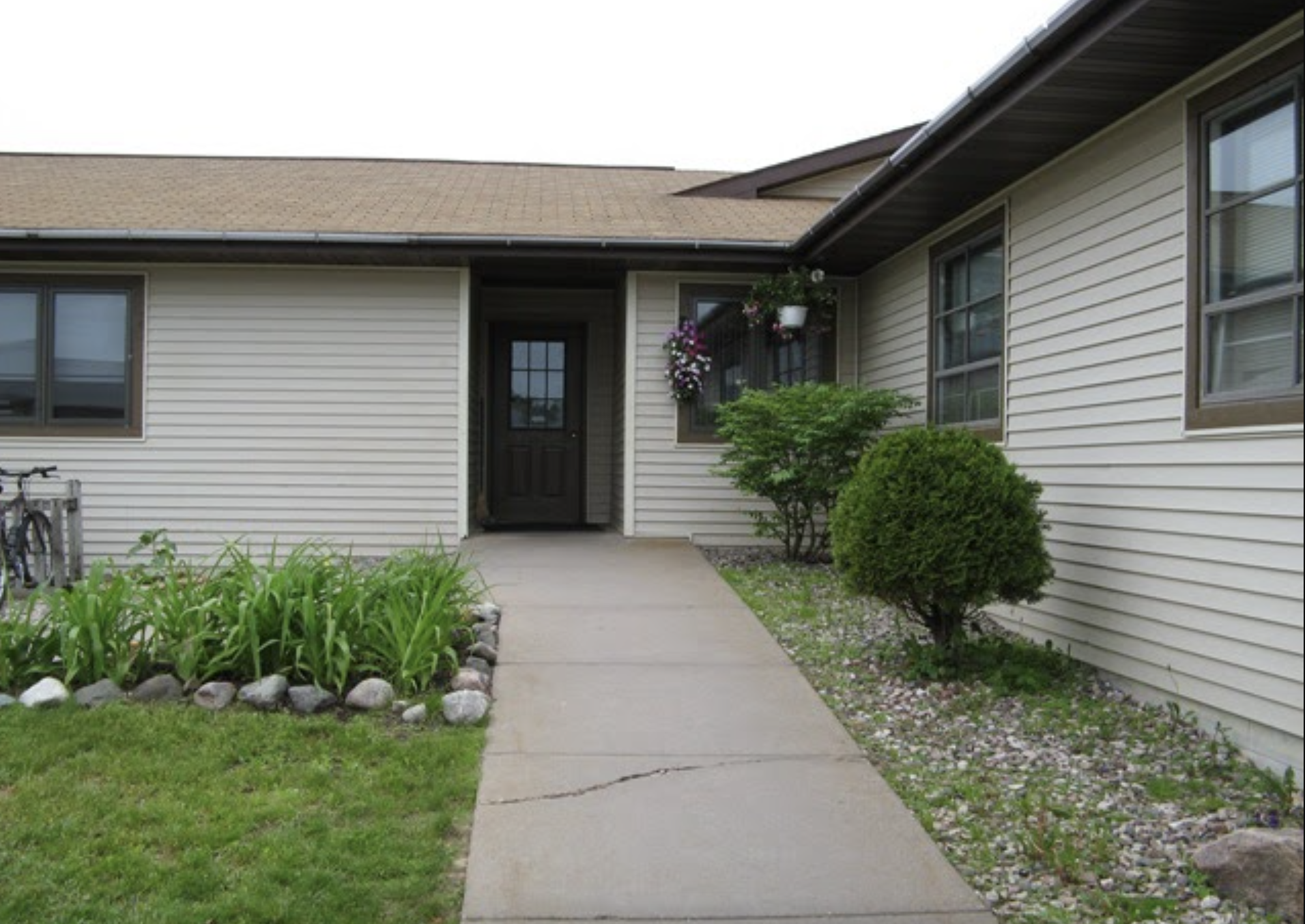 A simple and clean entrance to a recovery center with well-maintained greenery along the walkway, offering a peaceful environment.