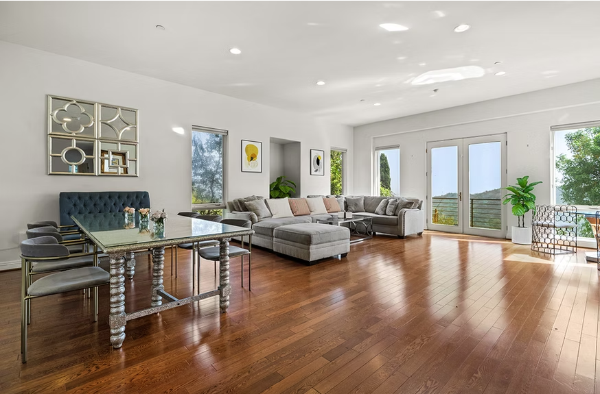 Bright living area with sectional sofa, dining table, and balcony view