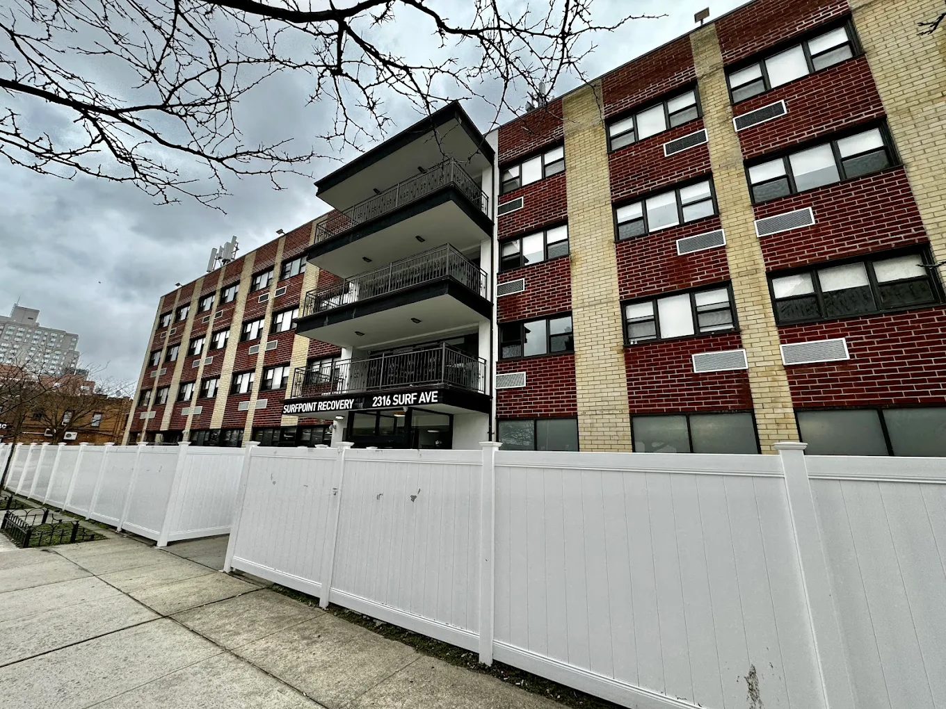 Multi-story brick rehab facility with balconies and white fence