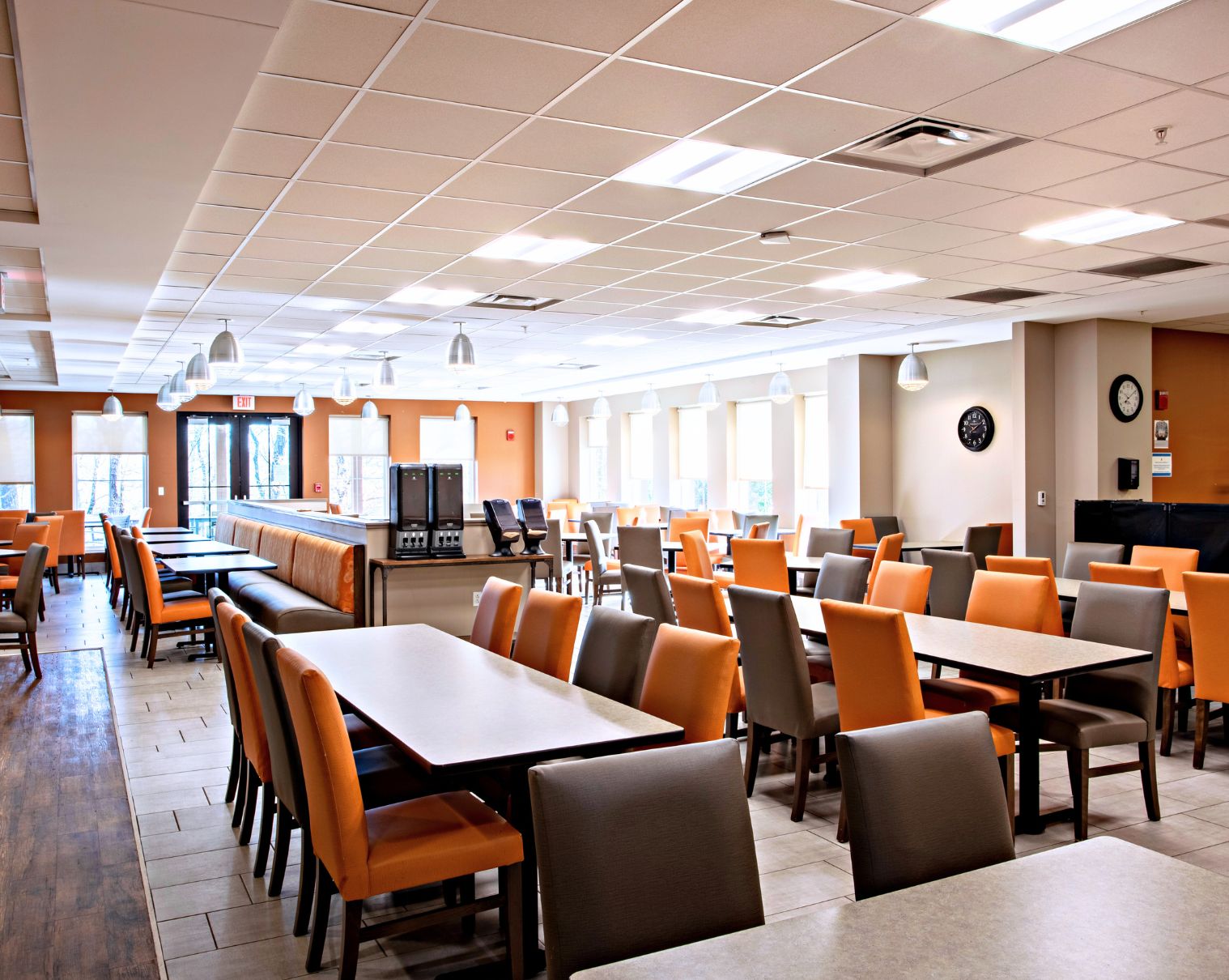 Large cafeteria with orange and gray chairs and ample lighting