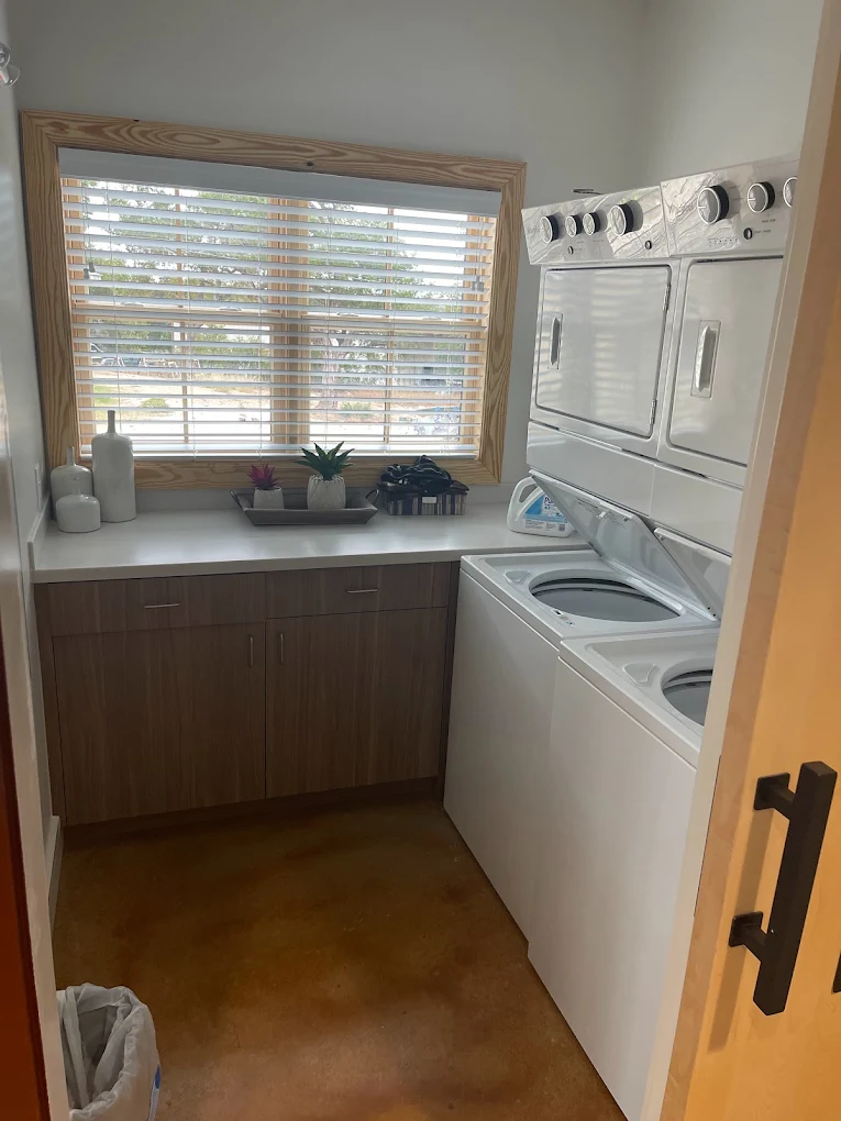 Laundry room with stacked washer dryer and cabinets