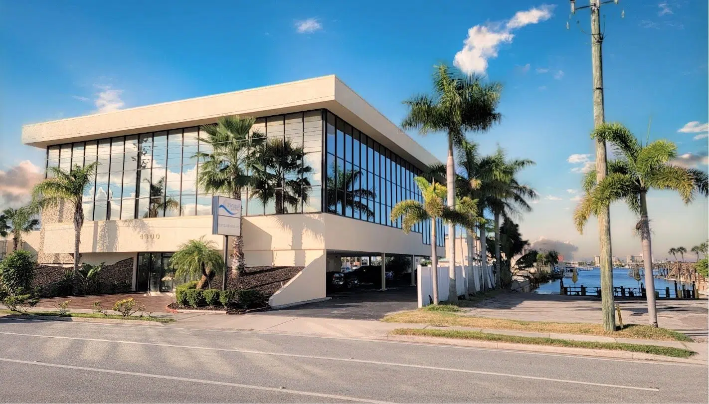 Exterior of Facilit with glass windows, surrounded by palm trees.