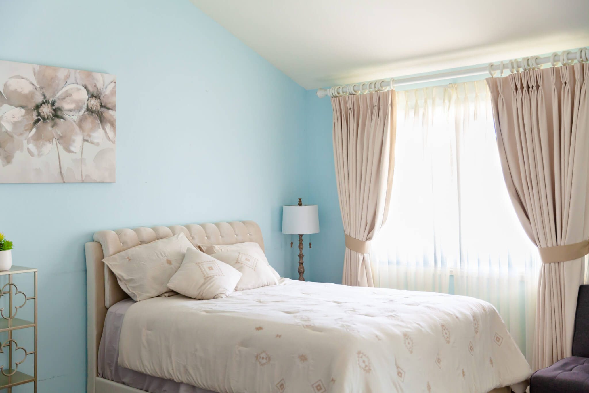 Light blue bedroom with queen bed and large curtained window