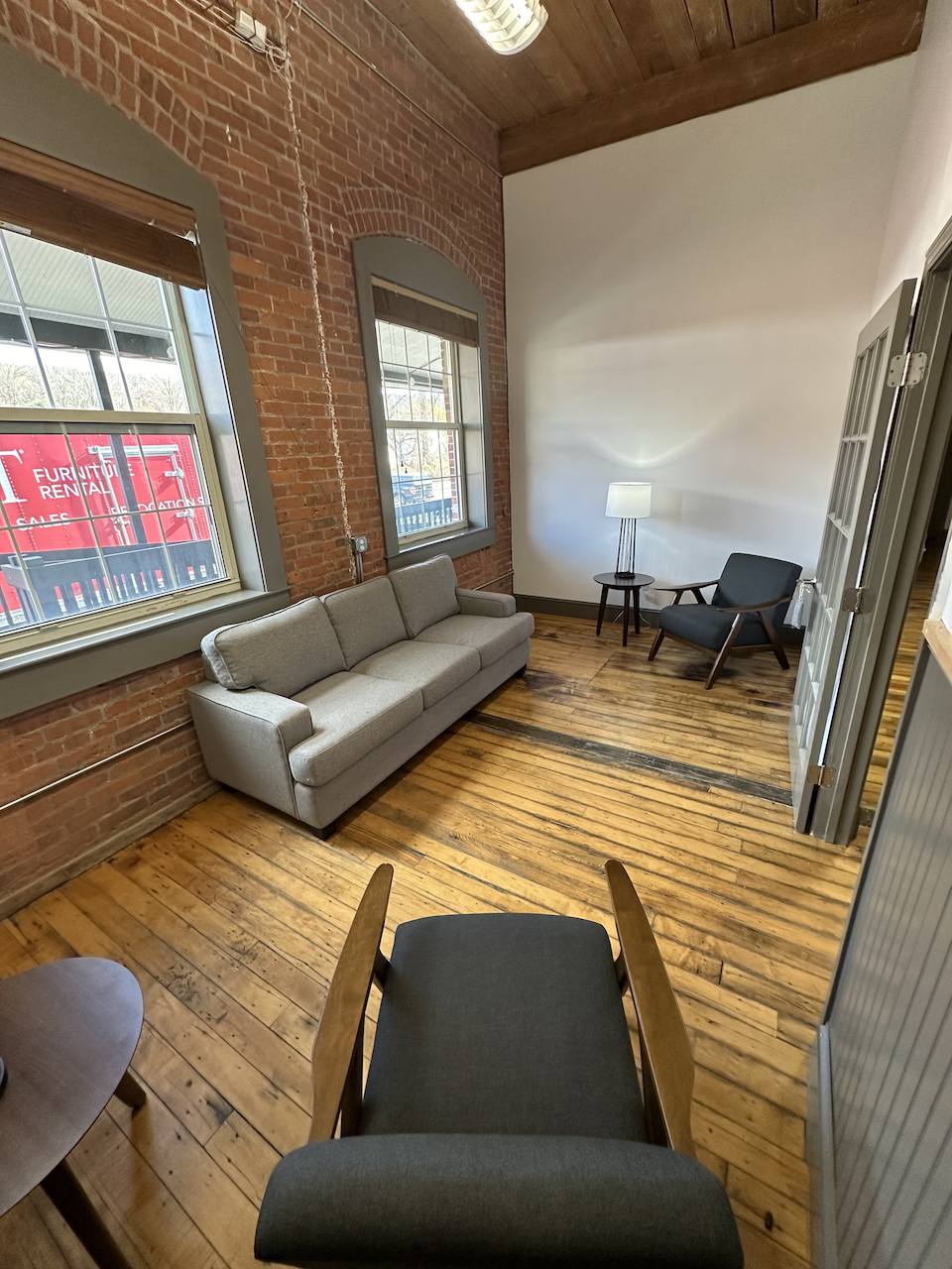 Private seating nook with gray sofa, chair, and natural light