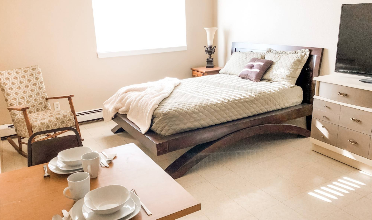 Private bedroom with bed, chair, tableware, and natural light