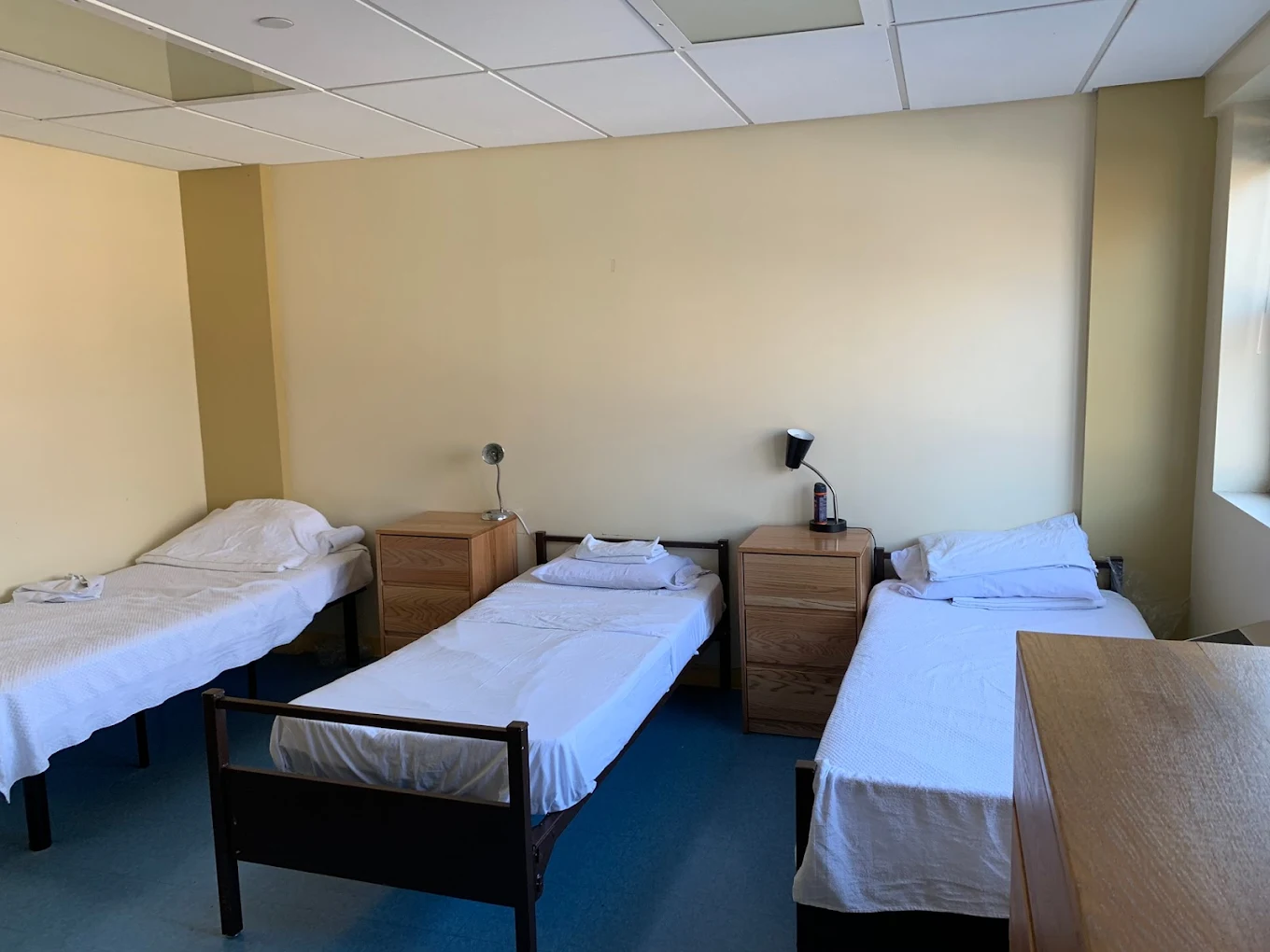 Room with three beds and small wooden nightstands