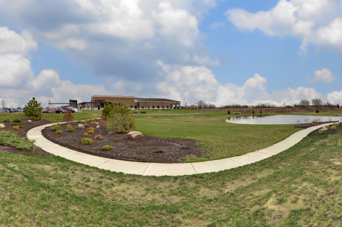 Pathway curving around grassy field and pond