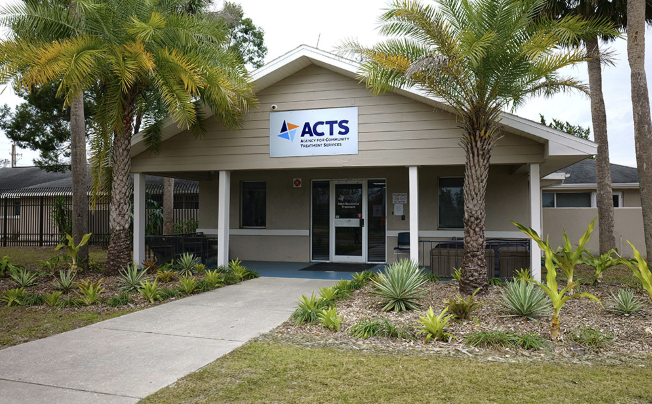ACTS facility entrance surrounded by palm trees and landscaping