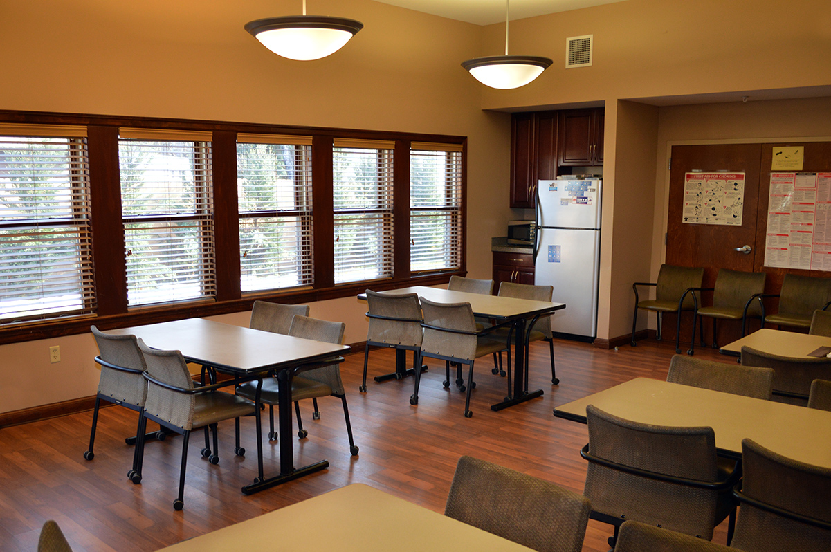 Dining room with tables, chairs, and a small kitchen area