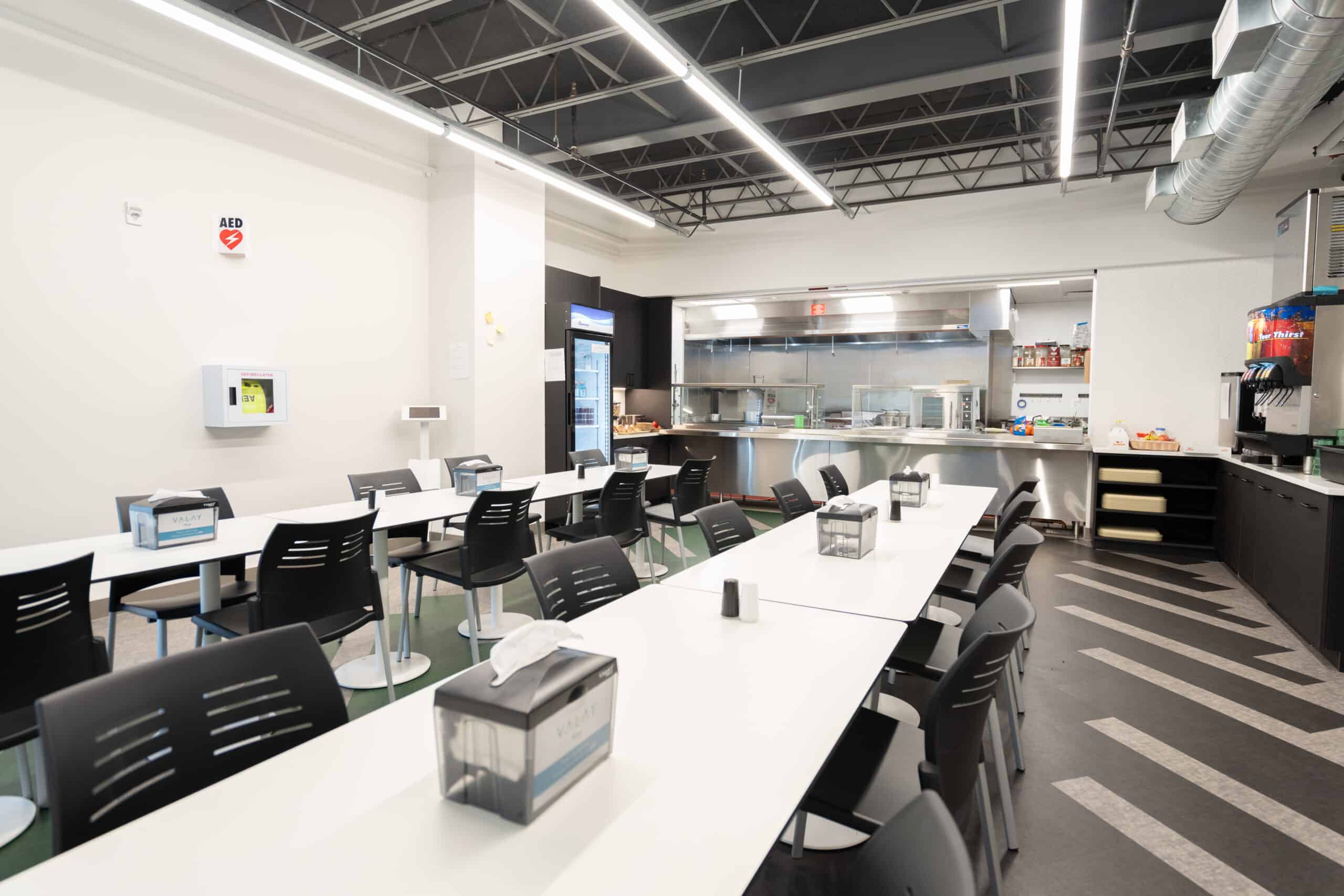 Modern cafeteria with white tables and food service counter