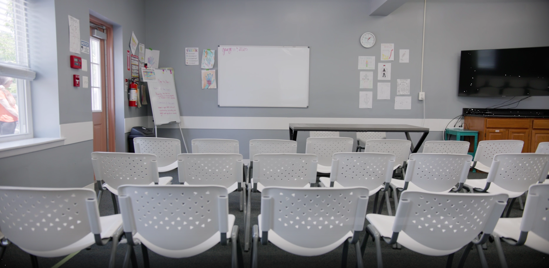 Group therapy classroom with chairs, whiteboard, and TV