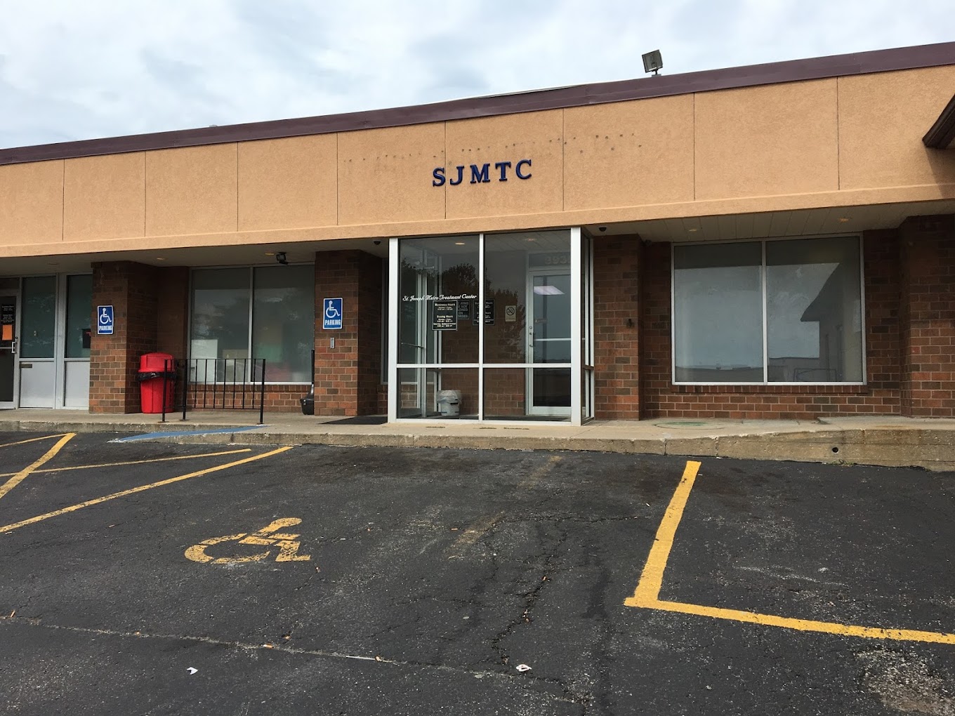 Exterior of SJMTC with glass doors, brick walls, and handicap parking.